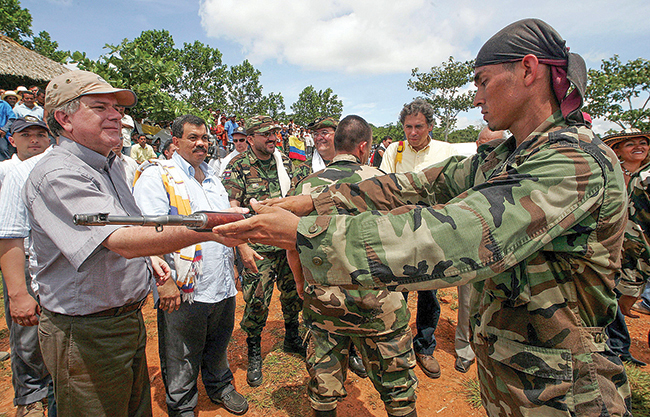 Colombian Peace Commissioner Luis Carlos Restrepo (left) receives a weapon from a member of the right-wing paramilitary group United Self Defenses of Colombia on June 15, 2005, in Valencia, Colombia. One in 10 Colombians remains displaced as peace begins to take hold in the country. But humans weren’t the only victims of the five-decade armed conflict.