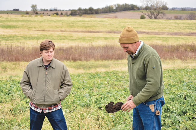 Farmer Seth Watkins (right) shows a sample of his soil to Climate Change Program Associate Mark Conway of the Stanley Center. Watkins, after implementing sustainable agriculture practices, has seen his soil organic levels hover around 4 to 6 percent, which has helped make his land more resilient to climate change.