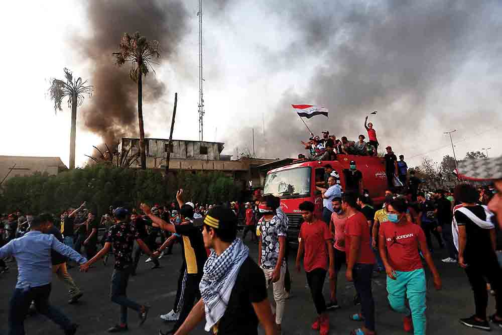 Iraqi protesters stand on a fire truck during an antigovernment demonstration on September 7, 2018, near the burnt building of the government office in Basra, Iraq. The protests that swept across southern and central Iraq in summer 2018 emerged partially as an outpouring of anger against Baghdad’s failure to deliver on promises of economic revitalization and development.