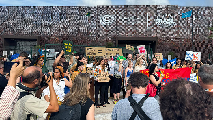 Group of people with signs standing outside a building.
